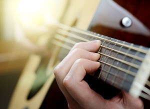 man's hands playing acoustic guitar, close up